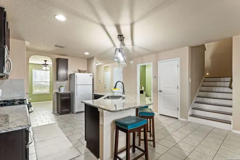 a kitchen with stainless steel appliances kitchen island granite countertop a refrigerator and a sink