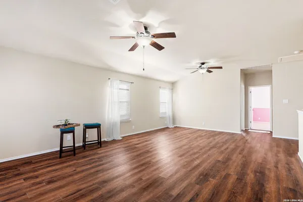 a view of an empty room with wooden floor and a ceiling fan