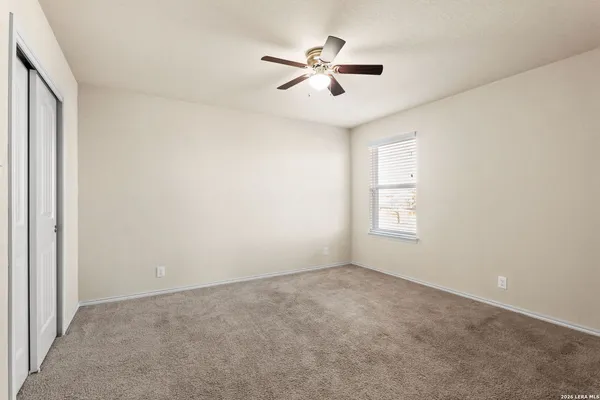 an empty room with ceiling fan and windows