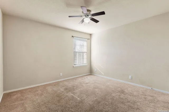 an empty room with a window and a ceiling fan