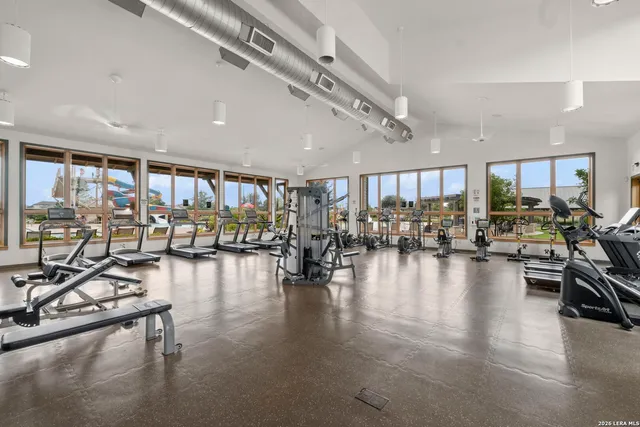 a gym room with gym equipment and a view of living room with furniture