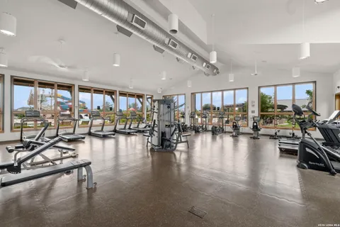 a gym room with gym equipment and a view of living room with furniture