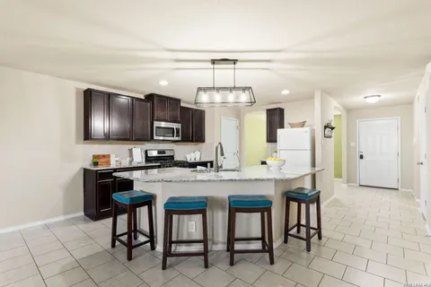 a kitchen with granite countertop a table chairs microwave and refrigerator
