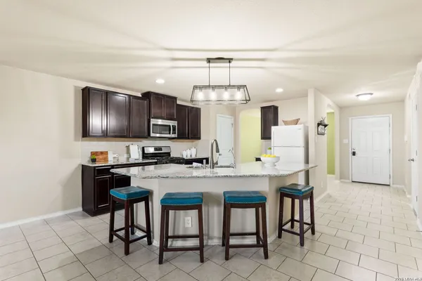 a kitchen with granite countertop a table chairs microwave and refrigerator
