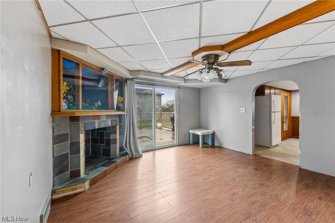 1470 Collar Price Road Hubbard, OH 44425 - Photo 9 of 23 Empty room with light wood-type flooring, a drop ceiling, ceiling fan, and a tile fireplace