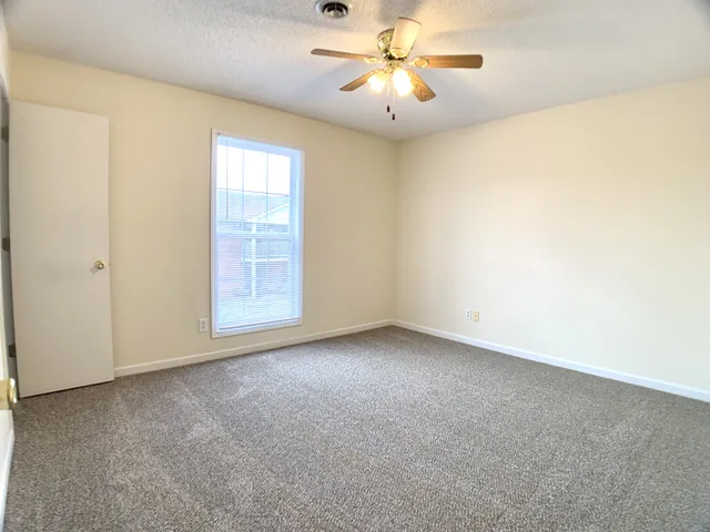 an empty room with a window and a fan