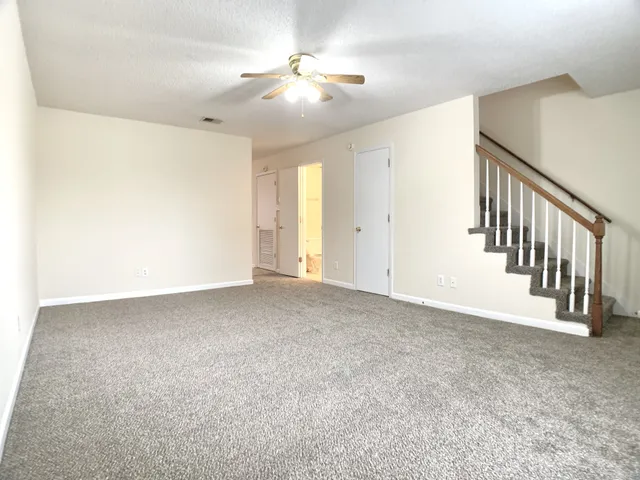 a view of an empty room with a chandelier fan