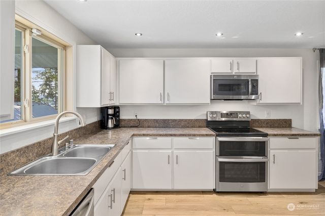 a kitchen with granite countertop a sink stainless steel appliances and cabinets
