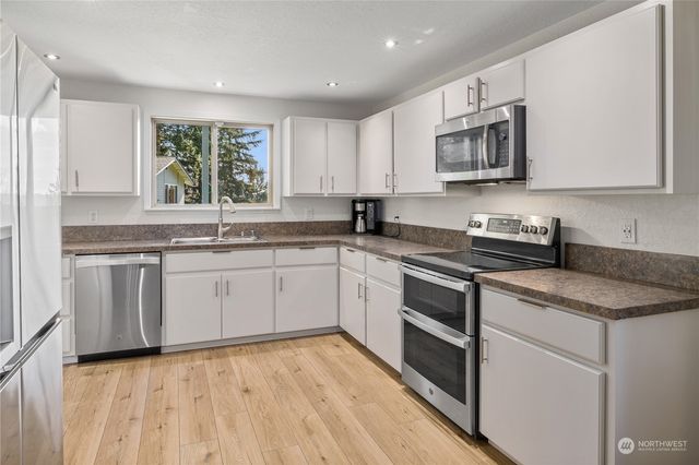 a kitchen with granite countertop white cabinets white appliances a sink and a window