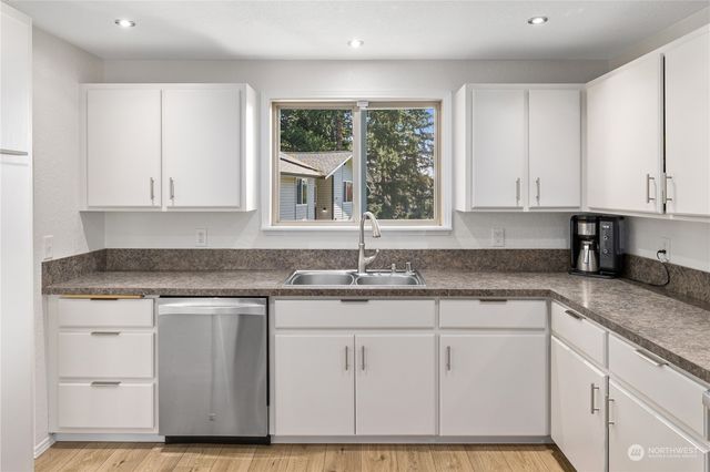 a kitchen with granite countertop white cabinets and a window