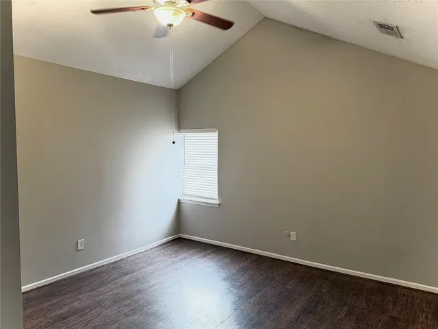 an empty room with a ceiling fan and wooden floor