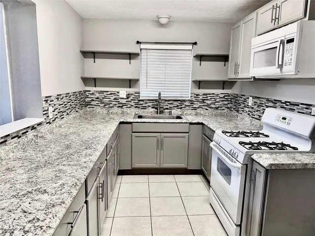 a kitchen with granite countertop a stove sink and cabinets