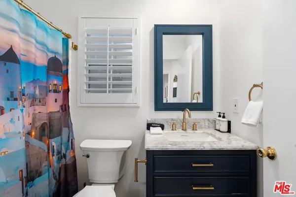 a bathroom with a granite countertop sink toilet and mirror