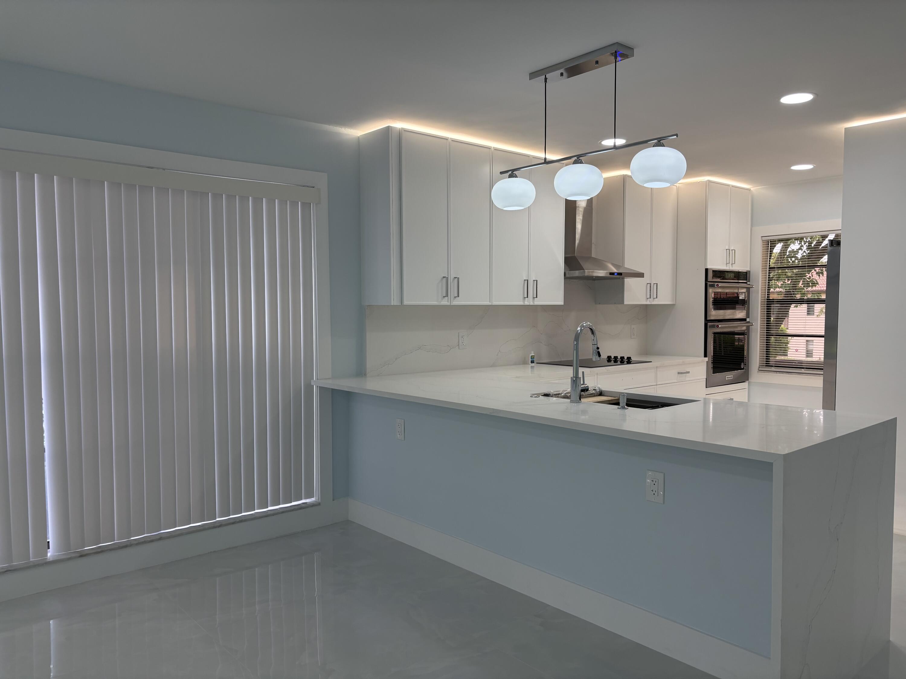 9266 Vista Del Lago, Unit 25H Boca Raton, FL 33428 - Photo 11 of 38 a kitchen with a sink chandelier and a stove
