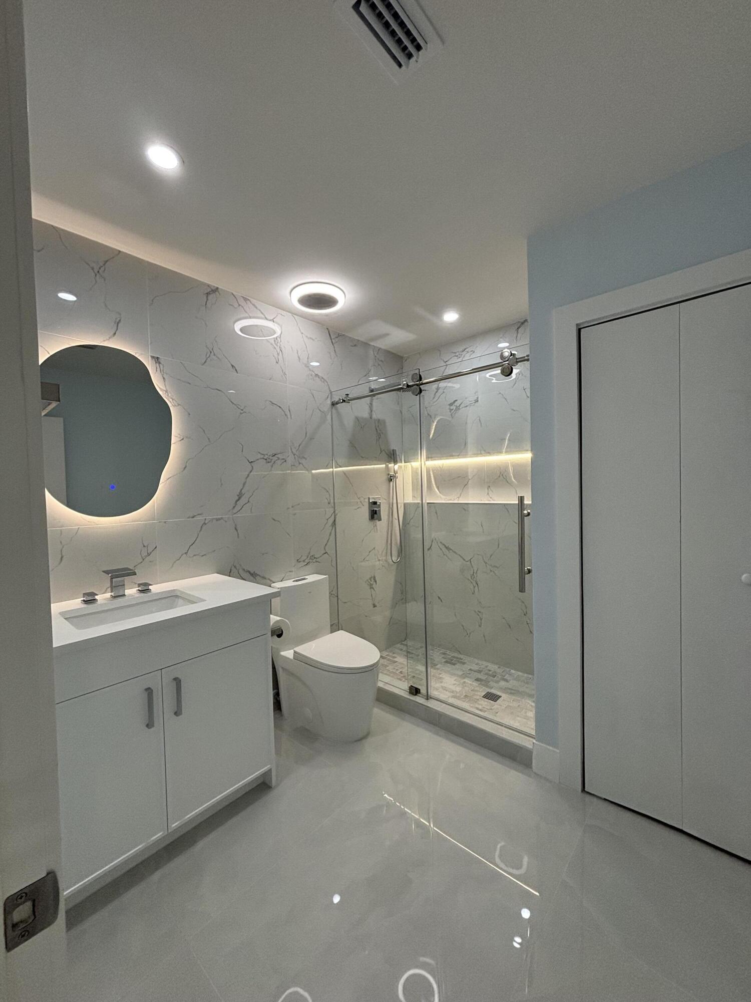 9266 Vista Del Lago, Unit 25H Boca Raton, FL 33428 - Photo 31 of 38 a bathroom with a granite countertop sink a toilet and shower