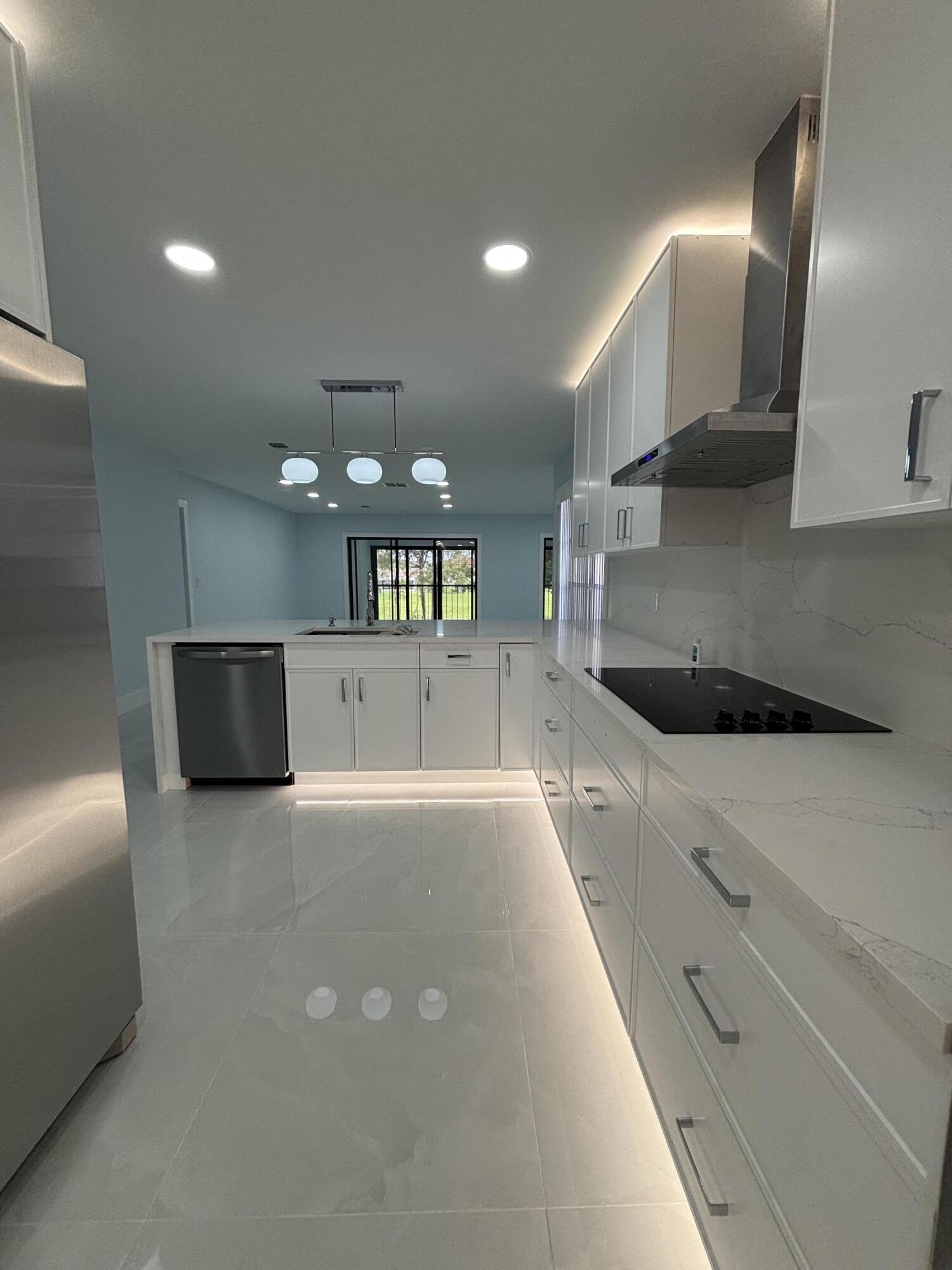 9266 Vista Del Lago, Unit 25H Boca Raton, FL 33428 - Photo 6 of 38 a large kitchen with stainless steel appliances a large counter top a stove and a refrigerator