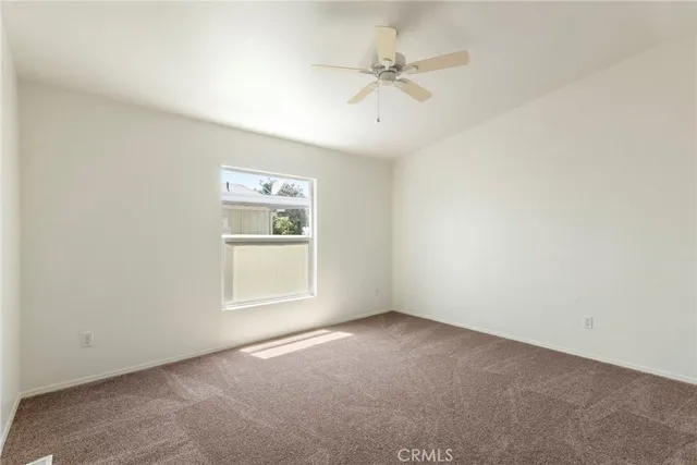 an empty room with a window and ceiling fan