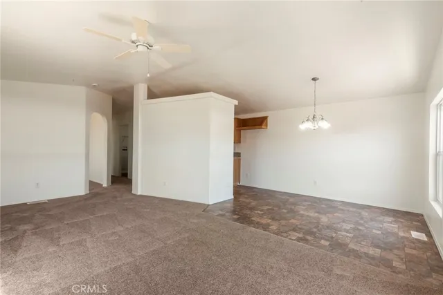 a view of an empty room with a chandelier fan