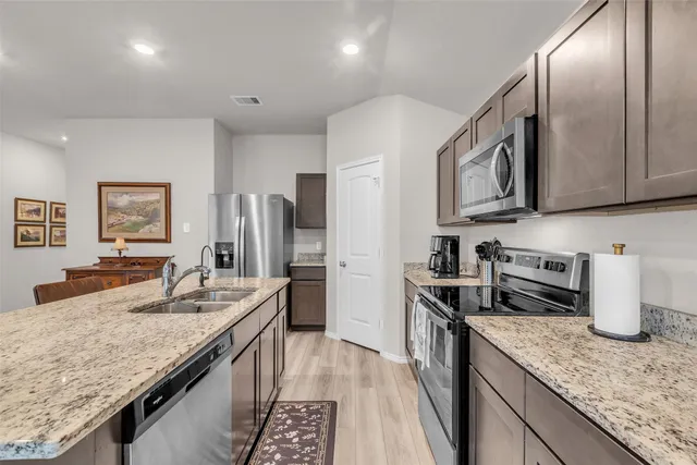 a kitchen with stainless steel appliances granite countertop a sink stove and refrigerator
