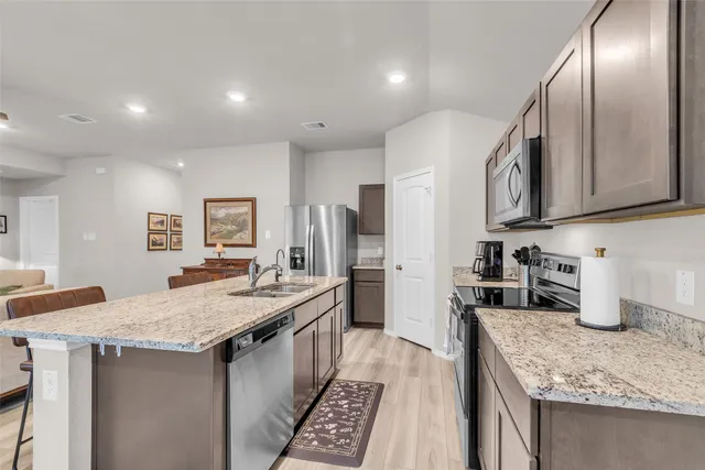 a kitchen with granite countertop a sink stove top oven and cabinets