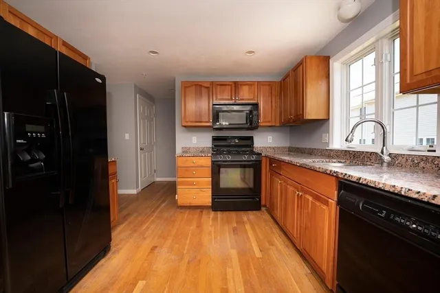 a kitchen with granite countertop a stove top oven a sink dishwasher and cabinets with wooden floor