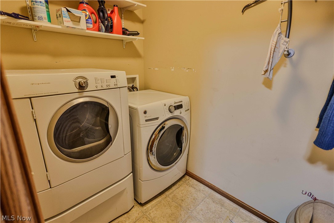 11154 Johnsford Road Southwest Beach City, OH 44608 - Photo 38 of 50 Dedicated laundry area featuring a front-loading washer and dryer, wall-mounted shelving, and tile flooring