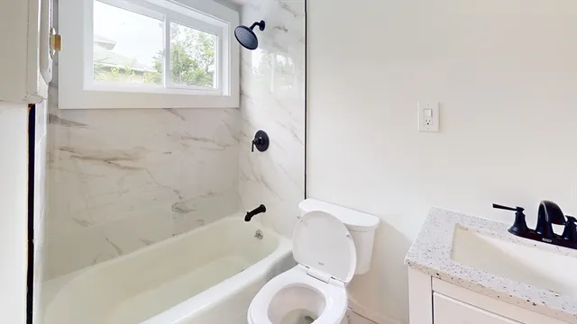 a bathroom with a toilet sink vanity and bathtub