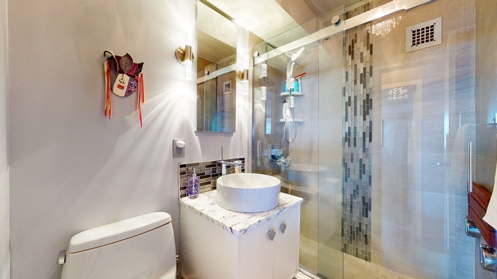 8 Whittier Place, Unit 16BFURNISH Boston, MA 02114 - Photo 7 of 7 a bathroom with a granite countertop sink a toilet and shower curtain