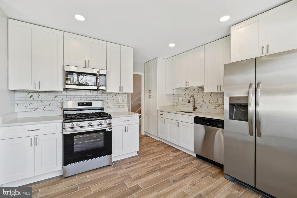 11514 Yates Street Silver Spring, MD 20902 - Photo 12 of 30 a kitchen with cabinets stainless steel appliances and wooden floor