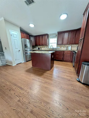 a living room with stainless steel appliances furniture a refrigerator and a kitchen view
