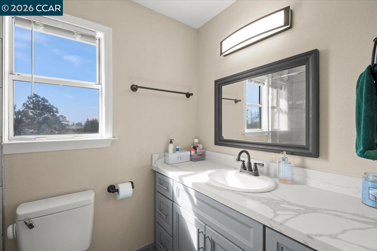 24685 Fuhrman Road Acampo, CA 95220 - Photo 32 of 58 a bathroom with a granite countertop sink a toilet and a mirror