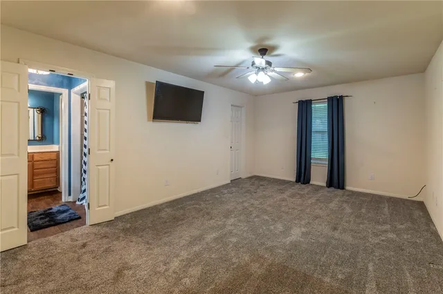 a view of an empty room with wooden floor and a ceiling fan