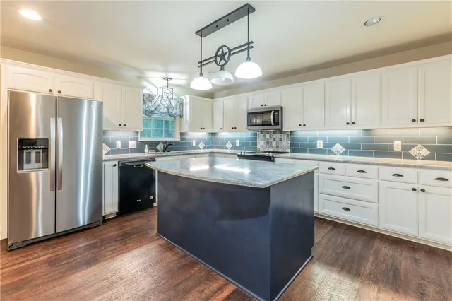 a kitchen with kitchen island granite countertop a sink a counter space stainless steel appliances and cabinets