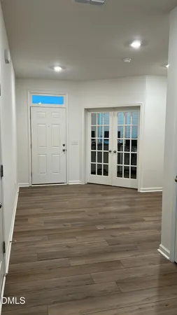 a view of an empty room with wooden floor and windows