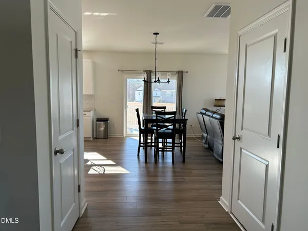 a view of a dining room and livingroom with furniture wooden floor a chandelier
