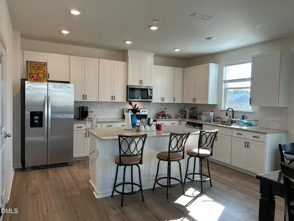 a kitchen with granite countertop a center island stainless steel appliances cabinets and a window