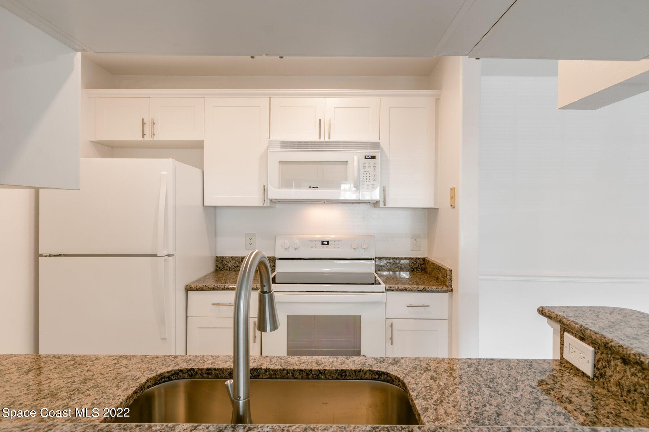 7667 North Wickham Road, Unit 703 Melbourne, FL 32940 - Photo 15 of 40 a kitchen with a refrigerator a stove a microwave and cabinets