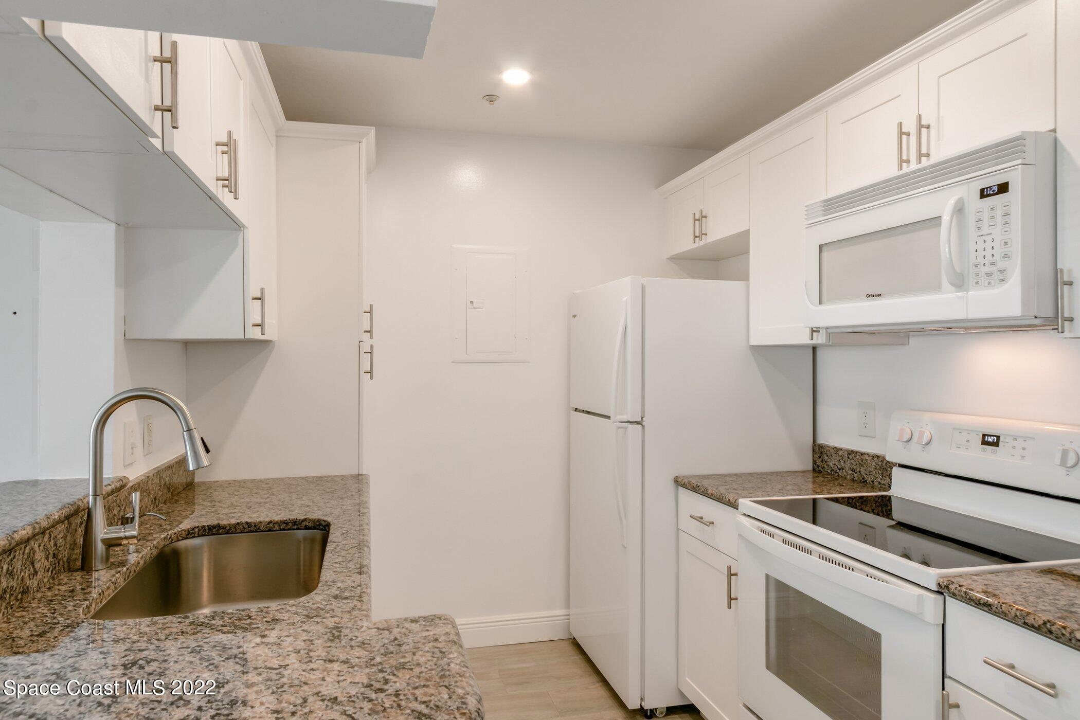7667 North Wickham Road, Unit 703 Melbourne, FL 32940 - Photo 16 of 40 a kitchen with stainless steel appliances granite countertop a sink stove and refrigerator