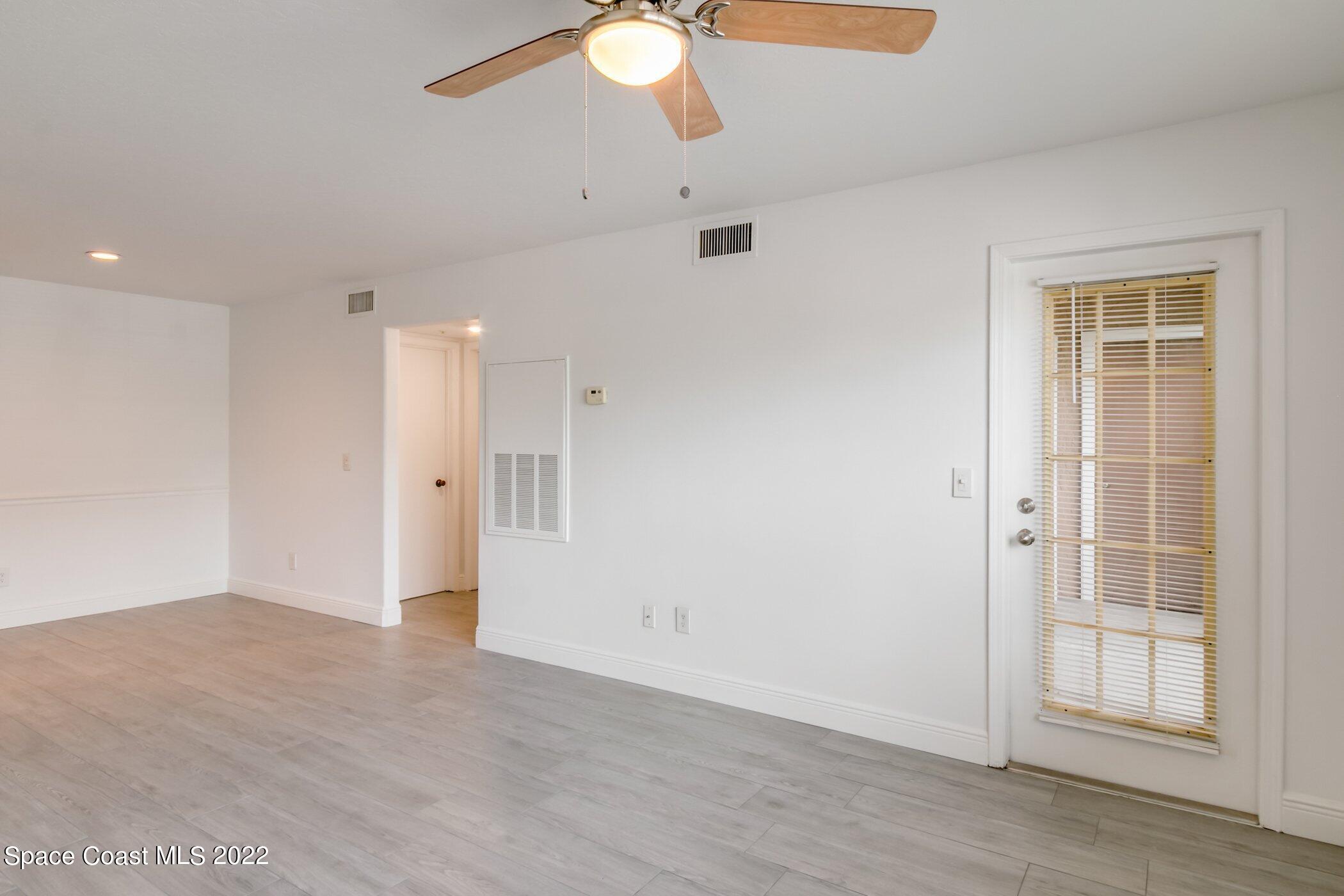 7667 North Wickham Road, Unit 703 Melbourne, FL 32940 - Photo 9 of 40 an empty room with wooden floor fan and windows