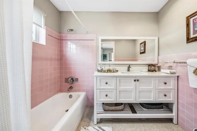 a bathroom with a tub sink double vanity and mirror