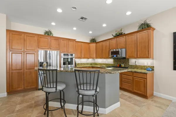 a kitchen with kitchen island granite countertop wooden cabinets and stainless steel appliances