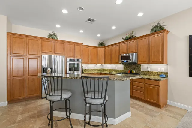 a kitchen with kitchen island granite countertop wooden cabinets and stainless steel appliances