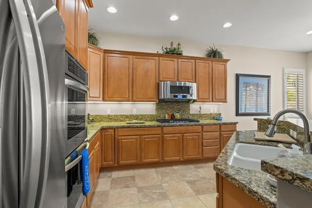 a kitchen with stainless steel appliances granite countertop a sink stove and cabinets