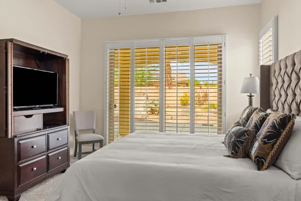 a bedroom with a bed and a flat tv screen on dresser