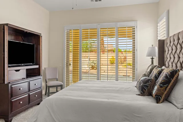 a bedroom with a bed and a flat tv screen on dresser