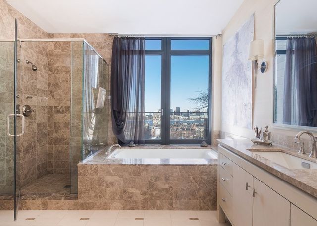 a spacious bathroom with a granite countertop sink a mirror and shower