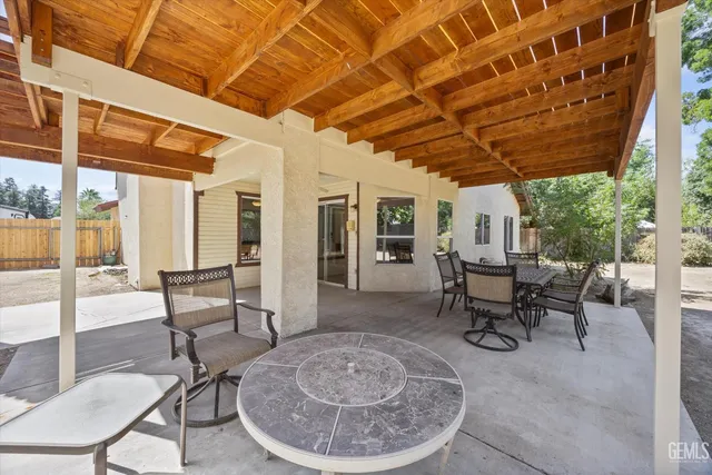 a view of a patio with table and chairs and couches with wooden floor and fence