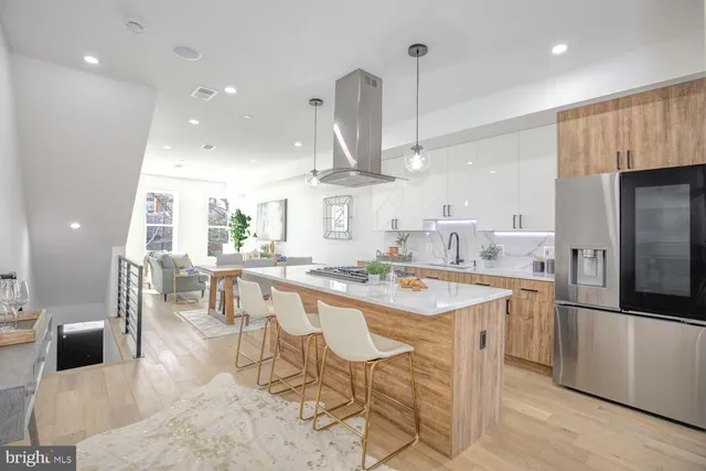 a kitchen with stainless steel appliances kitchen island granite countertop a table chairs and a refrigerator