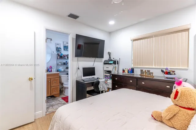 a bed room with a bed flat screen tv and a window