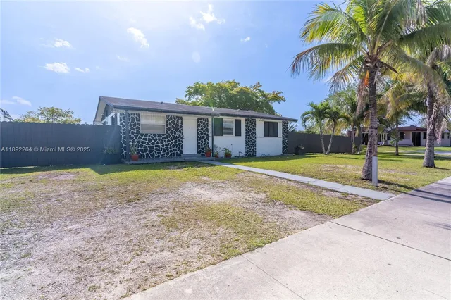 a view of a house with a yard and palm trees